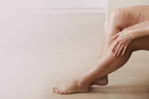 Painful varicose and spider veins on active womans legs, self-helping herself in overcoming the pain.